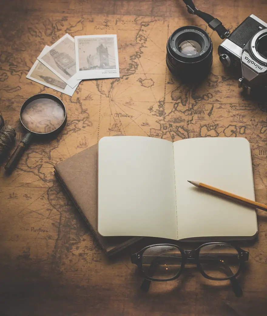 Mapa, fotos e caderno de viagem sobre a mesa